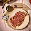 Load image into Gallery viewer, A jar of black Petrusco River Beluga caviar next to a cut steak
