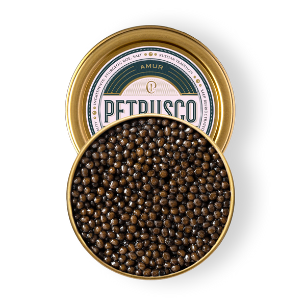 Open tin of Petrusco Amur caviar with gold lid showing glossy dark brown pearls, overhead on a white background