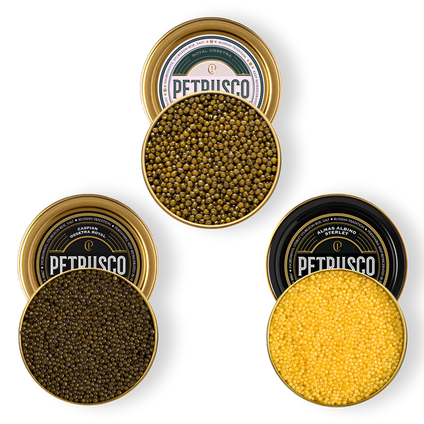 Three open gold tins of Petrusco caviar — golden-green Royal Ossetra, dark Caspian Ossetra Royal, and bright golden Almas Albino Sterlet — viewed from above