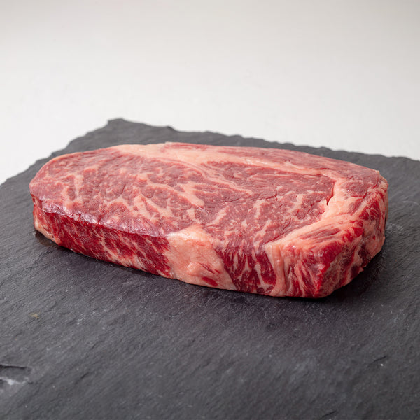 Grass-Fed Australian Wagyu Ribeye MS 8-9 on a dark slate surface with a white background