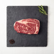 Load image into Gallery viewer, Raw steak on a slate board with rosemary and peppercorns
