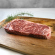 Load image into Gallery viewer, Raw steak on a wooden cutting board with herbs
