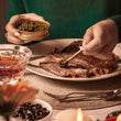 Load image into Gallery viewer, Someone putting black caviar on a cut up steak
