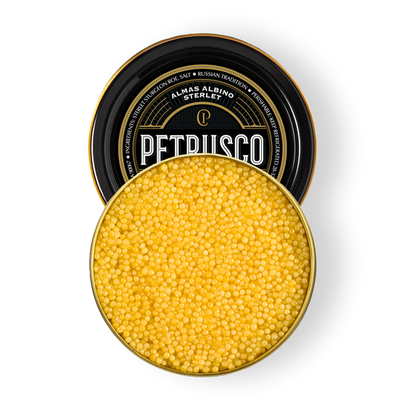 Open tin of Petrusco Almas Albino Sterlet caviar showing luminous golden pearls on a white background.